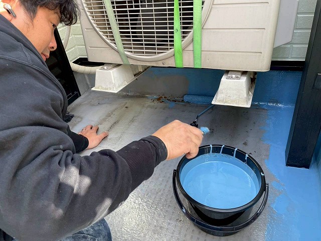 明石市のベランダで室外機を持ち上げている様子